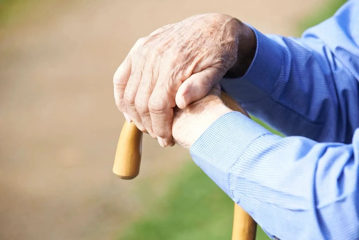 A close up of an elderly person holding onto a cane